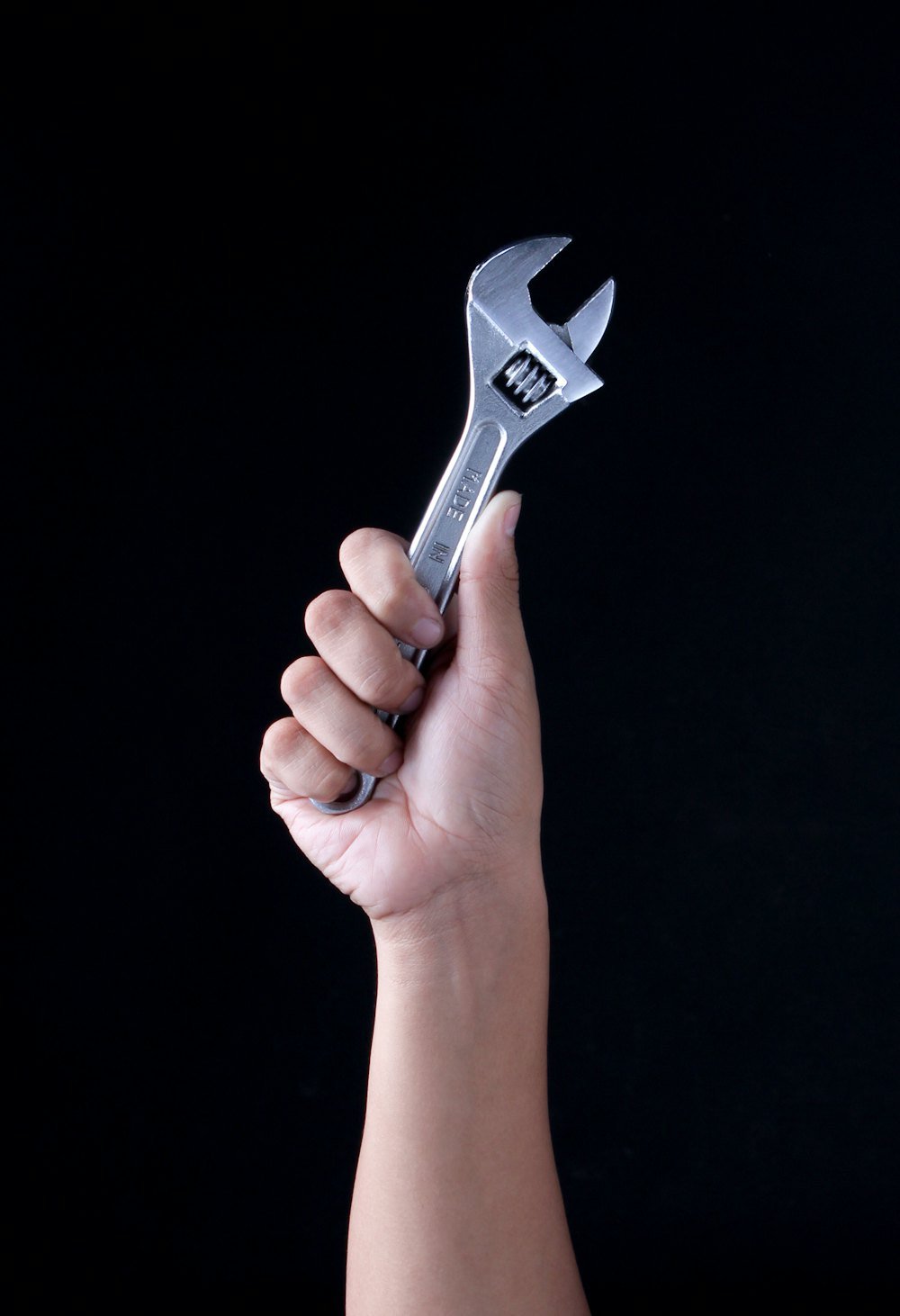 Mãos segurando uma chave de boca, representando o trabalho manual especializado